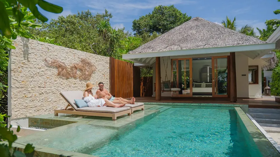 A villa with a private pool and loungers among tropical plants
