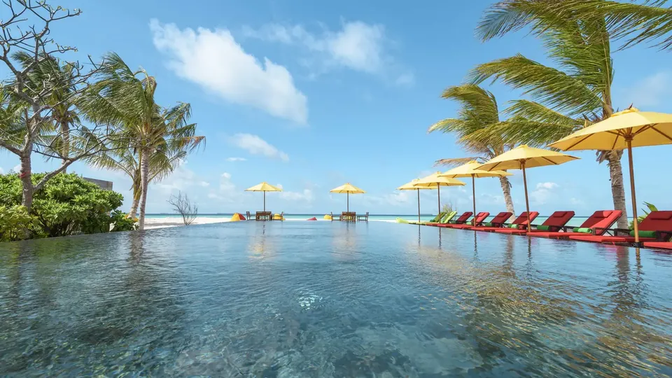 Ein langer Infinity-Pool mit gelben Sonnenschirmen und Liegen mit Blick aufs Meer