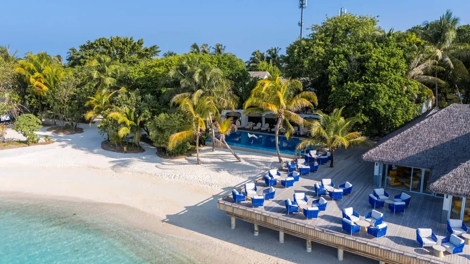 Blaue Sonnenliegen an einem sonnigen Strand neben einer ruhigen Lagune