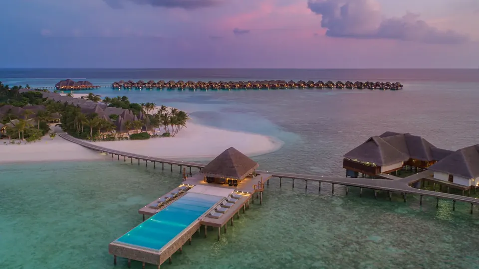 Overwater villas with private pools along a wooden jetty above a turquoise lagoon
