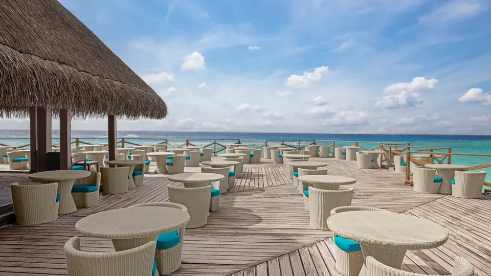 Deque de restaurante ao ar livre com mesas voltadas para o mar