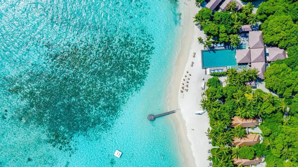 ภาพมุมสูงของชายหาดรีสอร์ตที่มีแนวปะการังอยู่ใกล้ชายฝั่ง