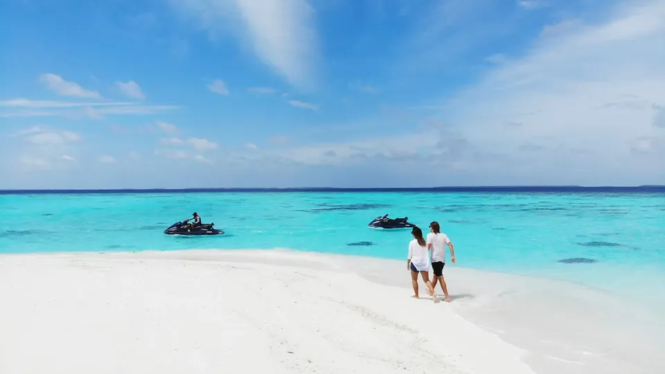 A couple in light summer clothes standing on a white beach