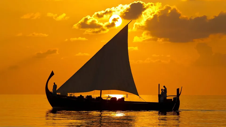 เงาเรือใบโดนีแบบดั้งเดิมแล่นผ่านฉากพระอาทิตย์ตกสีทอง