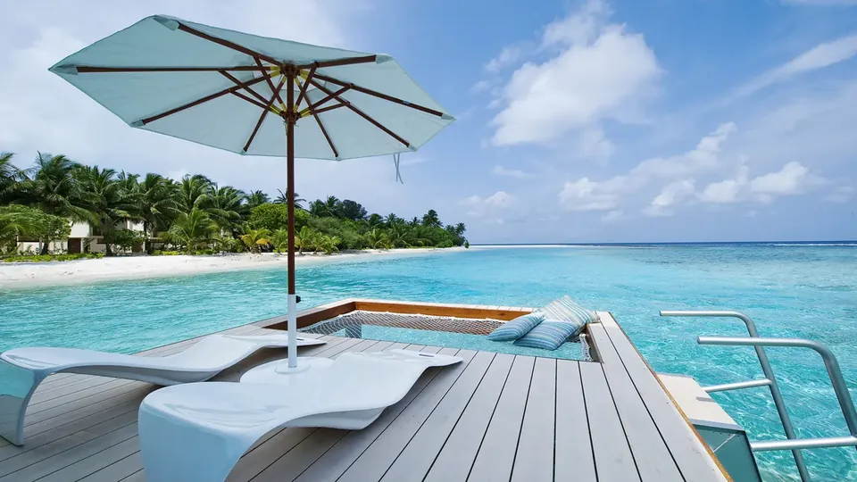 A shaded deck with loungers looking out over a calm blue lagoon